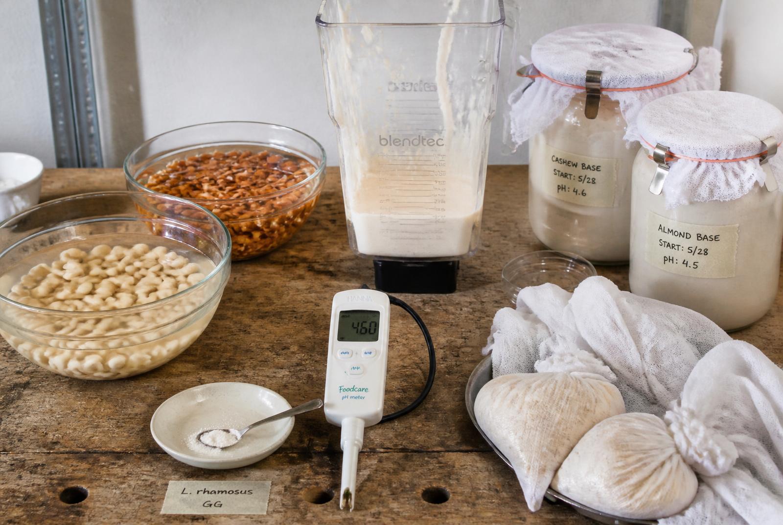 Mesa de trabajo con frutos secos activados, base triturada, bases fermentando en tarros, medidor de pH y telas de escurrido