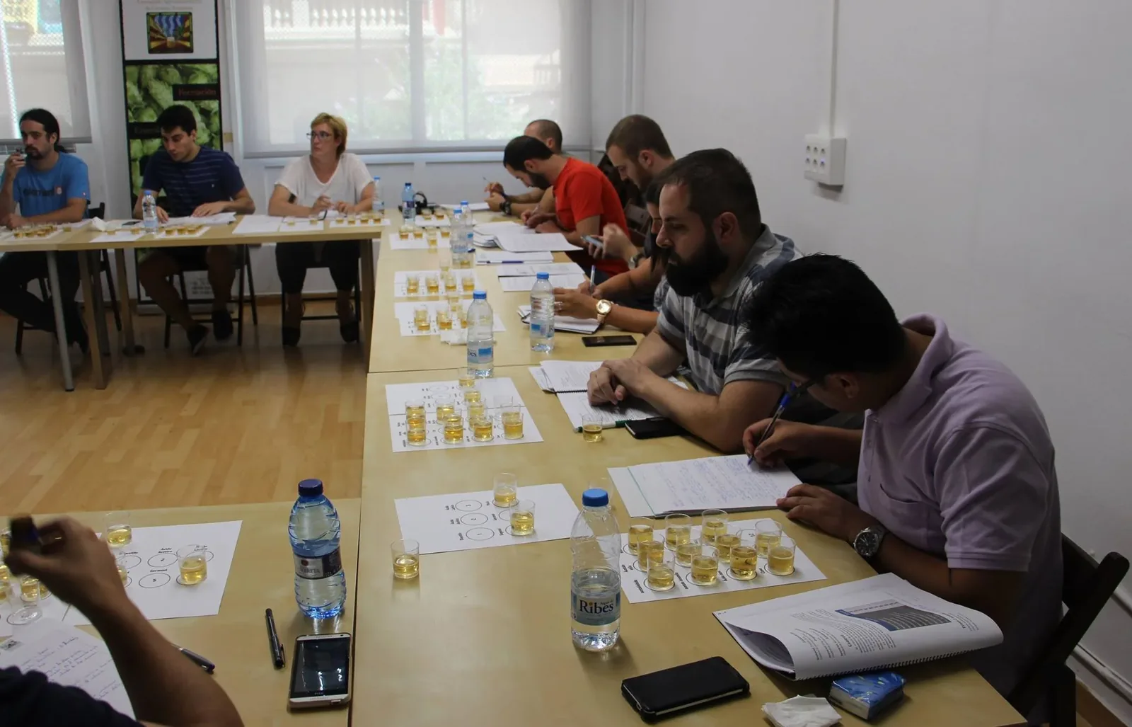 Aula con asistentes catando muestras de cerveza en copas durante el curso de defectos