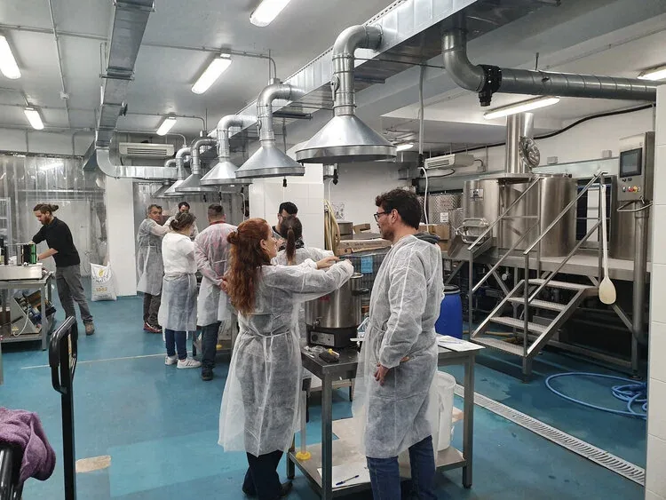 Grupo de alumnos trabajando alrededor de los equipos en la sala de elaboración